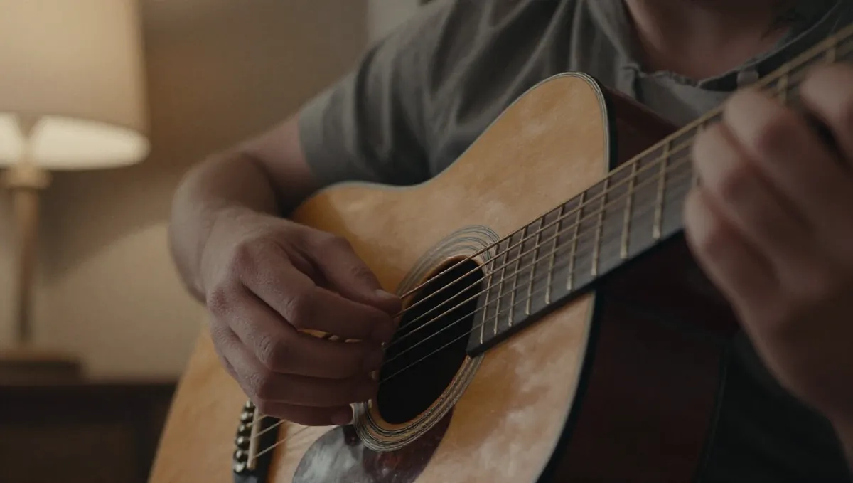 Fingerspitzen drücken Saiten nahe der Kopfplatte einer abgenutzten Akustikgitarre